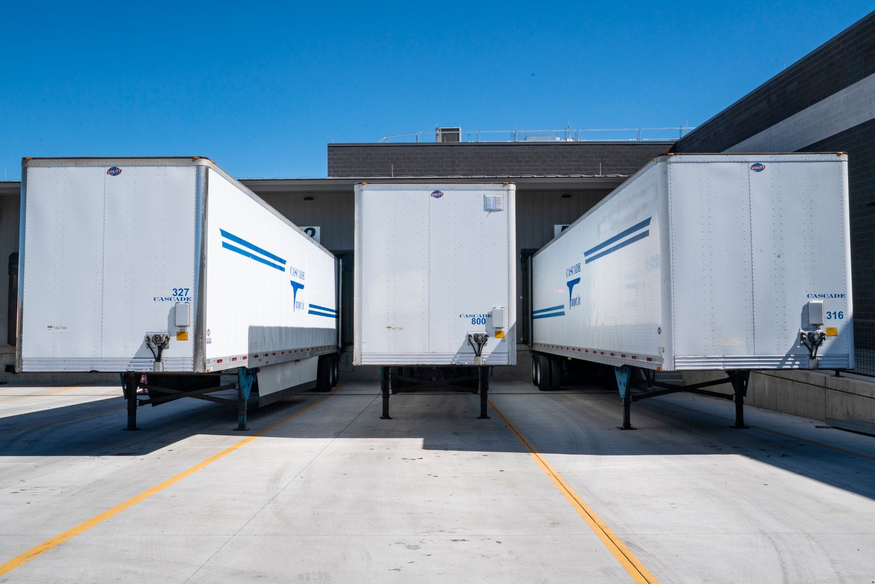 Cargo trailers parked at industrial loading docks under a clear sky