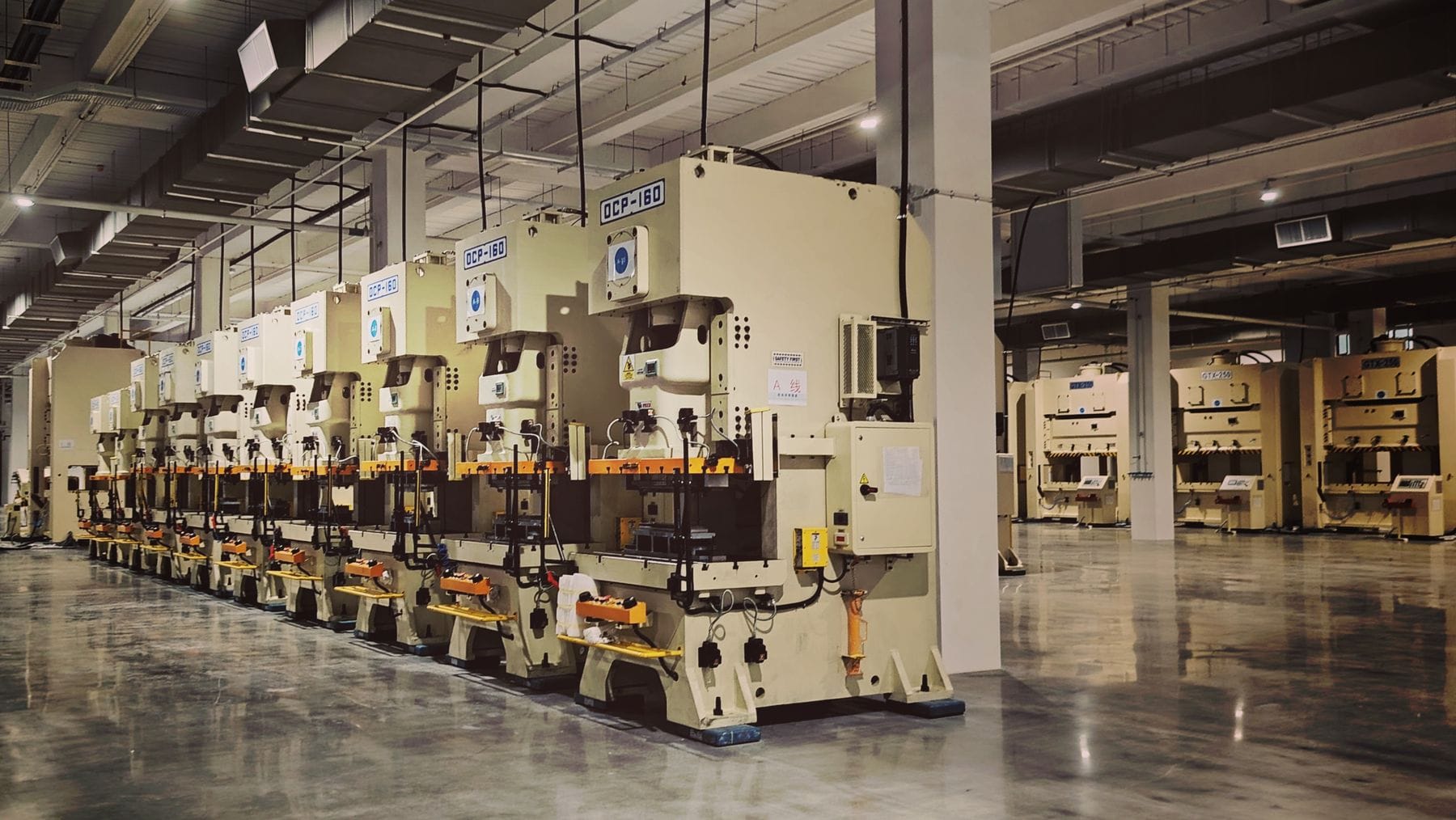 Row of industrial stamping presses on a clean manufacturing floor