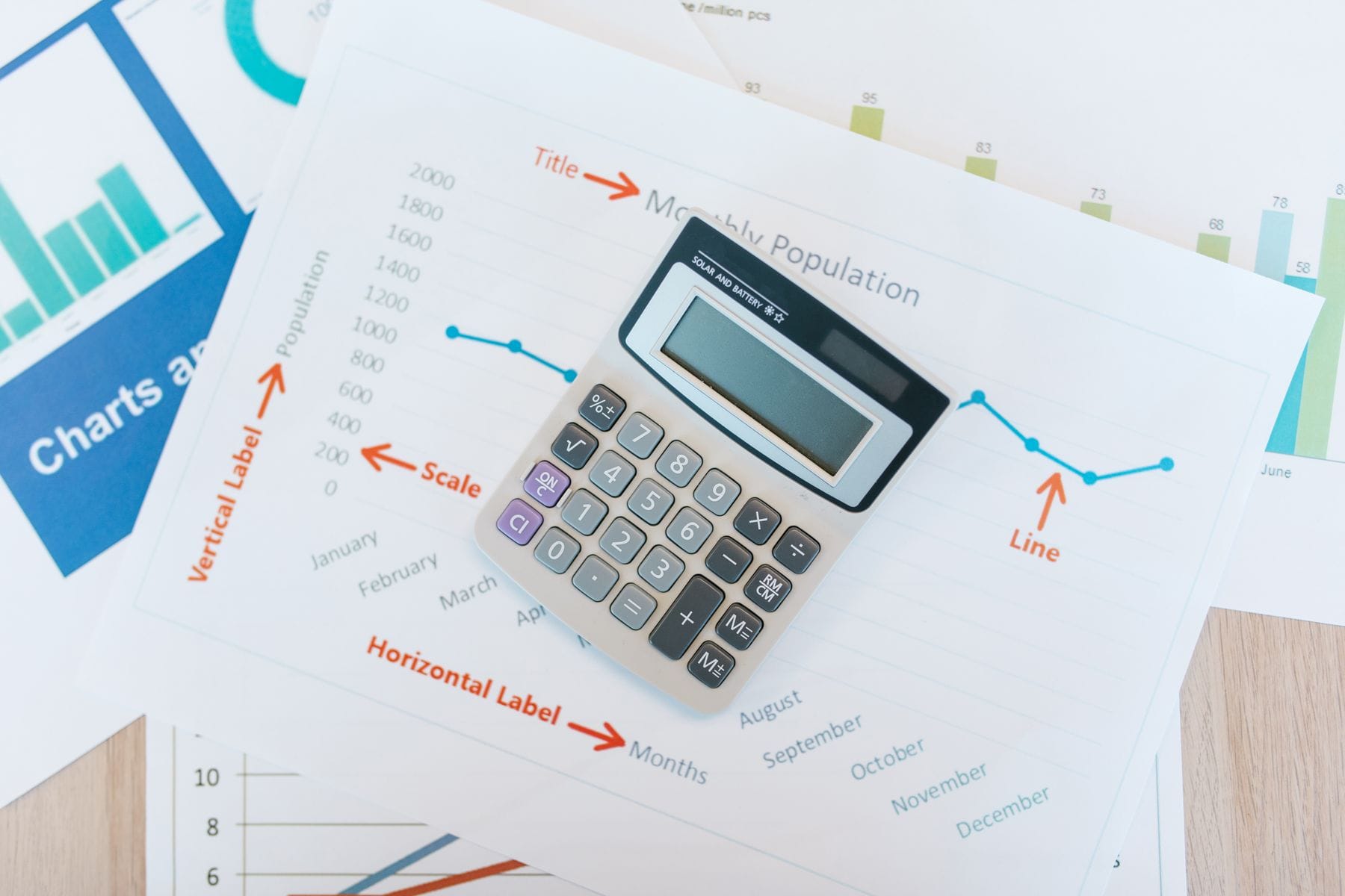 Calculator resting on printed cost charts and financial reports