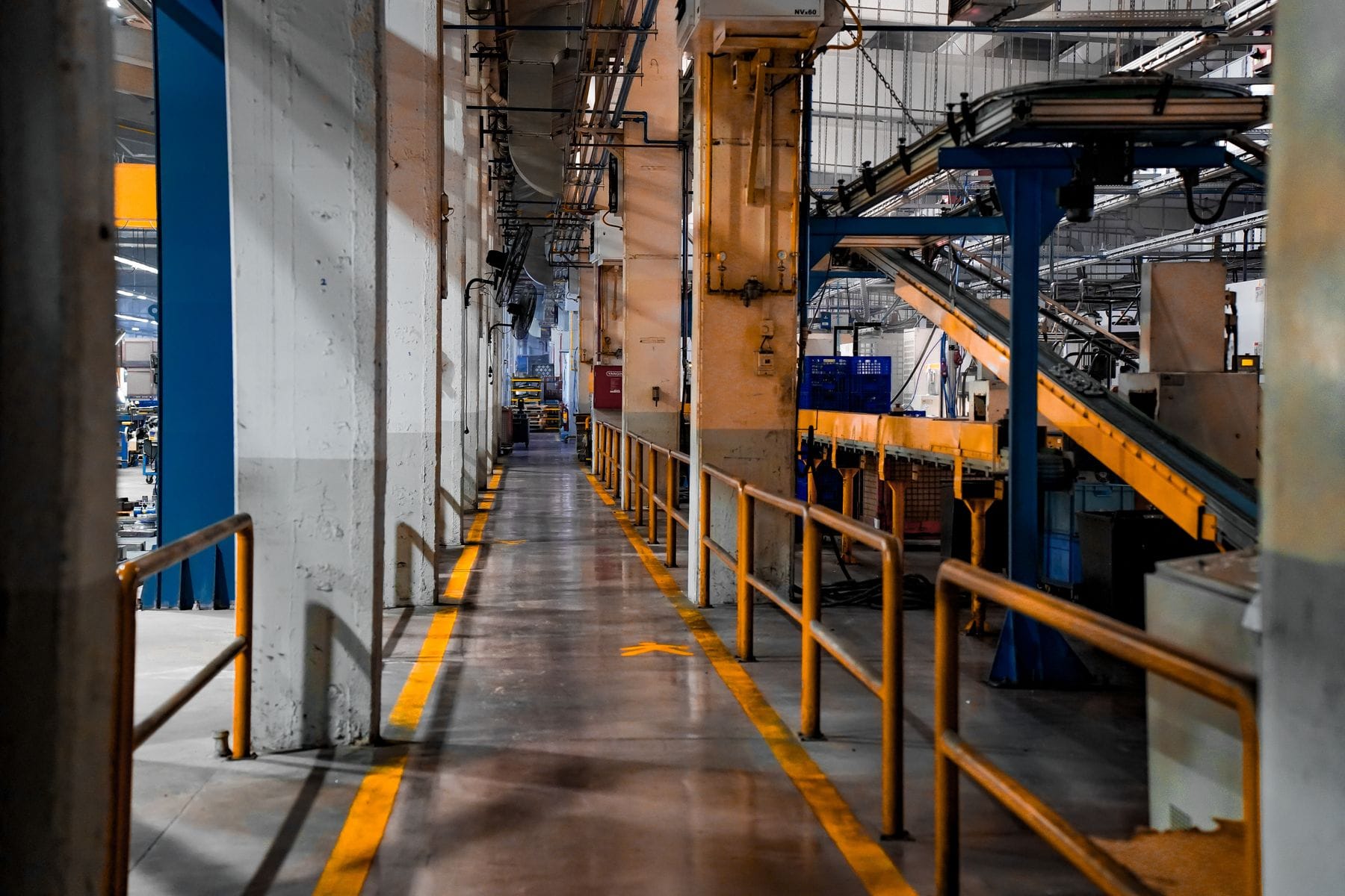 Elevated walkway with yellow railings above conveyor lines inside a factory