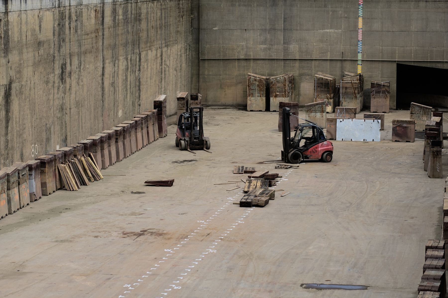 Forklifts parked in a large empty industrial building being cleared out