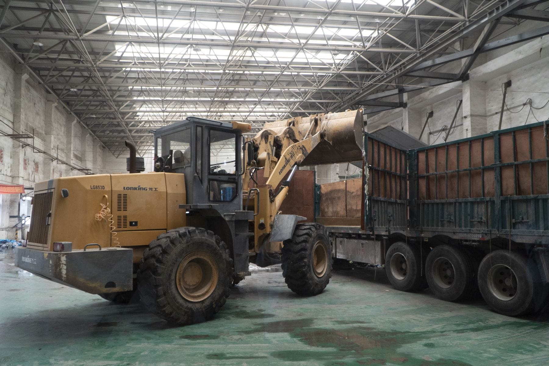Wheel loader moving material into a trailer inside an industrial building