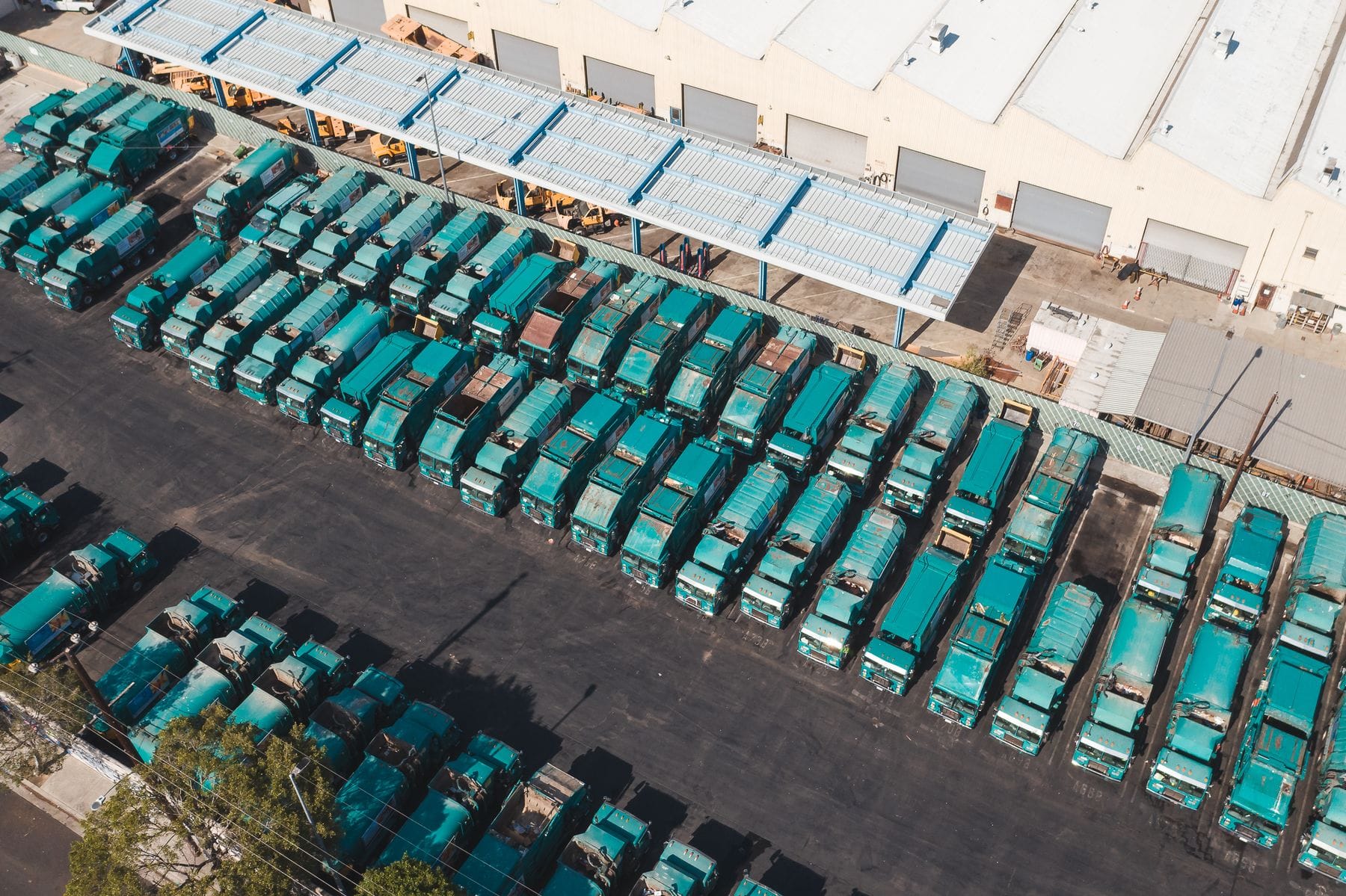 Rows of parked trucks beside a large distribution warehouse seen from above