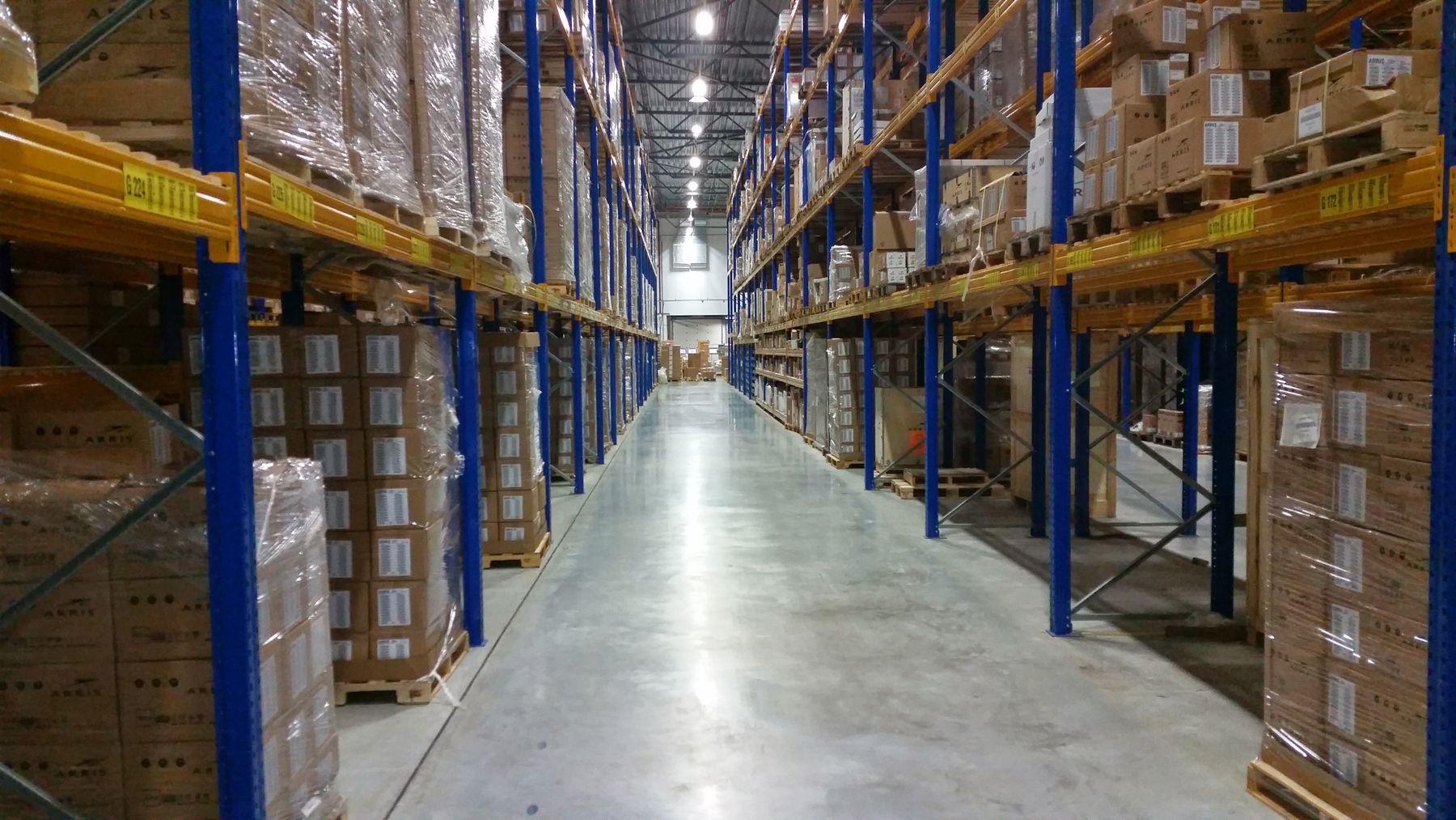 Wide warehouse aisle between tall racks of palletized boxes