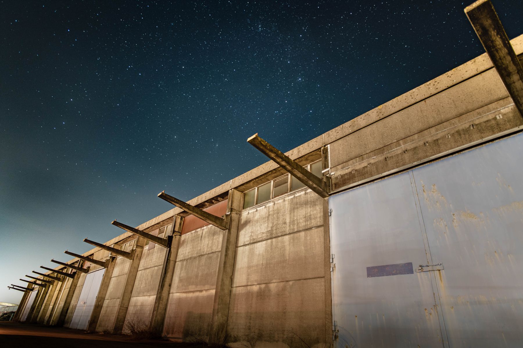 Concrete industrial building photographed at night under a starry sky