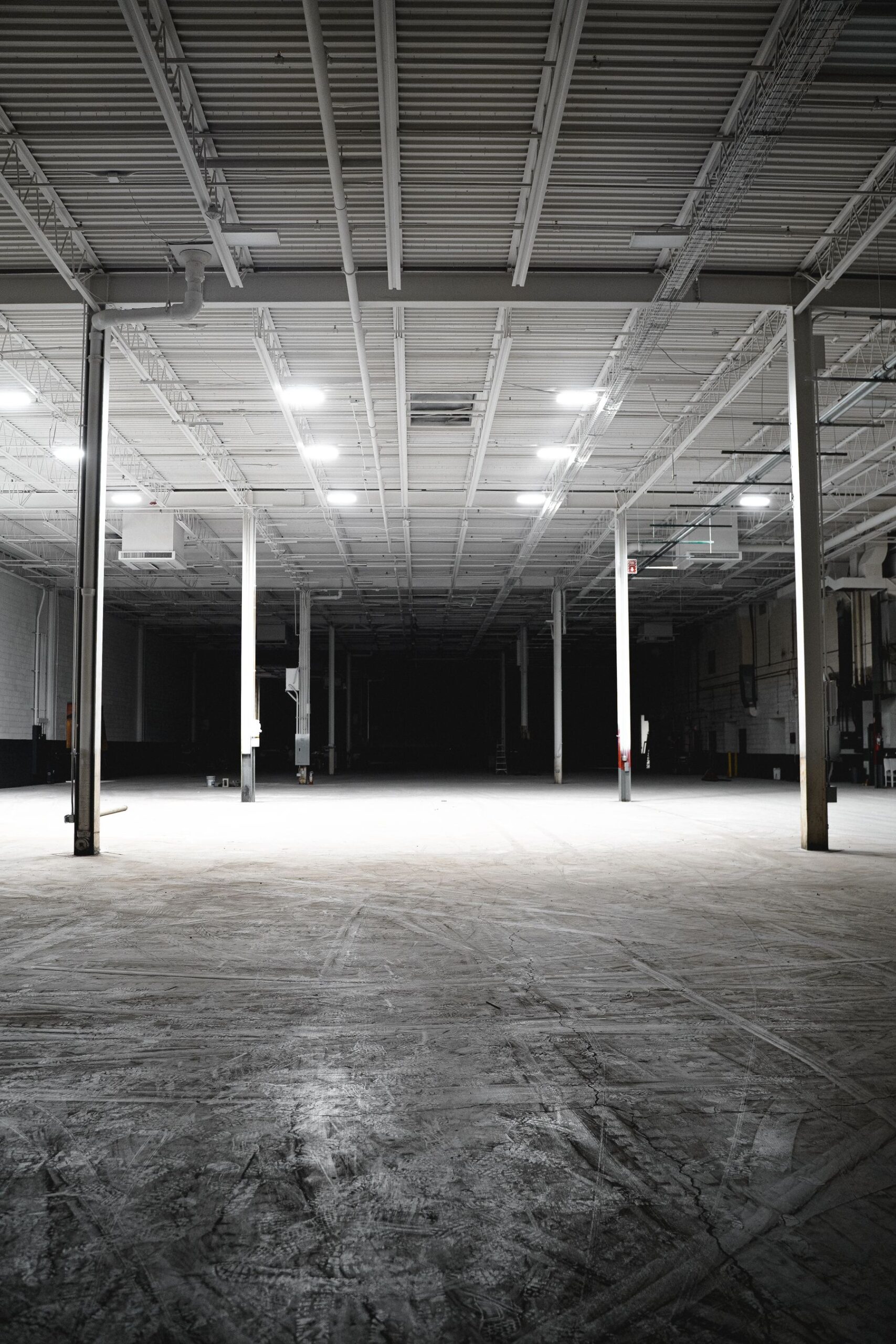 Vast empty warehouse interior under rows of overhead lights